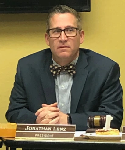 Jonathan Lenz seated at the school board table with his president nameplate